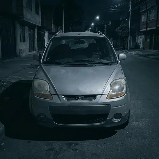 Carro gris parqueado de noche en una calle oscura, sin llamar la atención